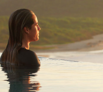 Person swimming in a pool looking at the sunrise.